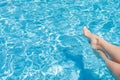 ÃÂ¡harming women`s legs are lowered into the clear water of the turquoise pool